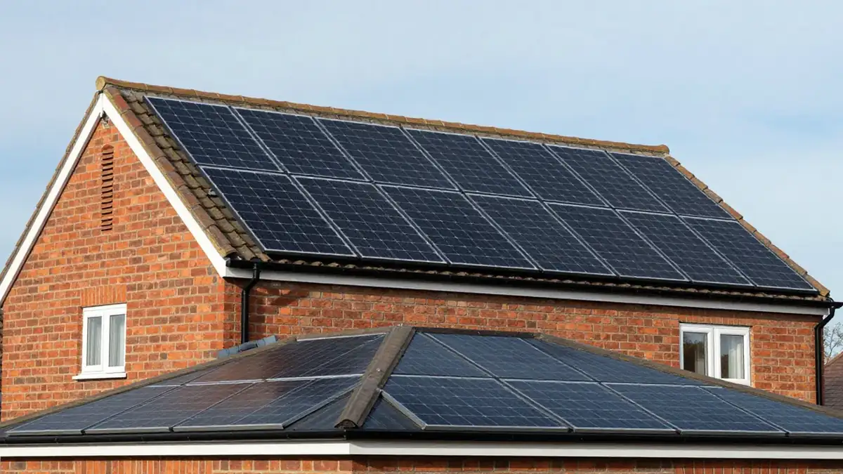 Brick house with solar panels on the main pitched roof and on a lower roof of the extension in front